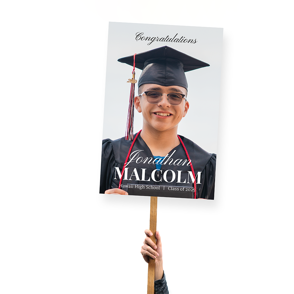 Graduation photo featuring a sign that reads "Congratulations Graduates!" with colorful decorations in the background.