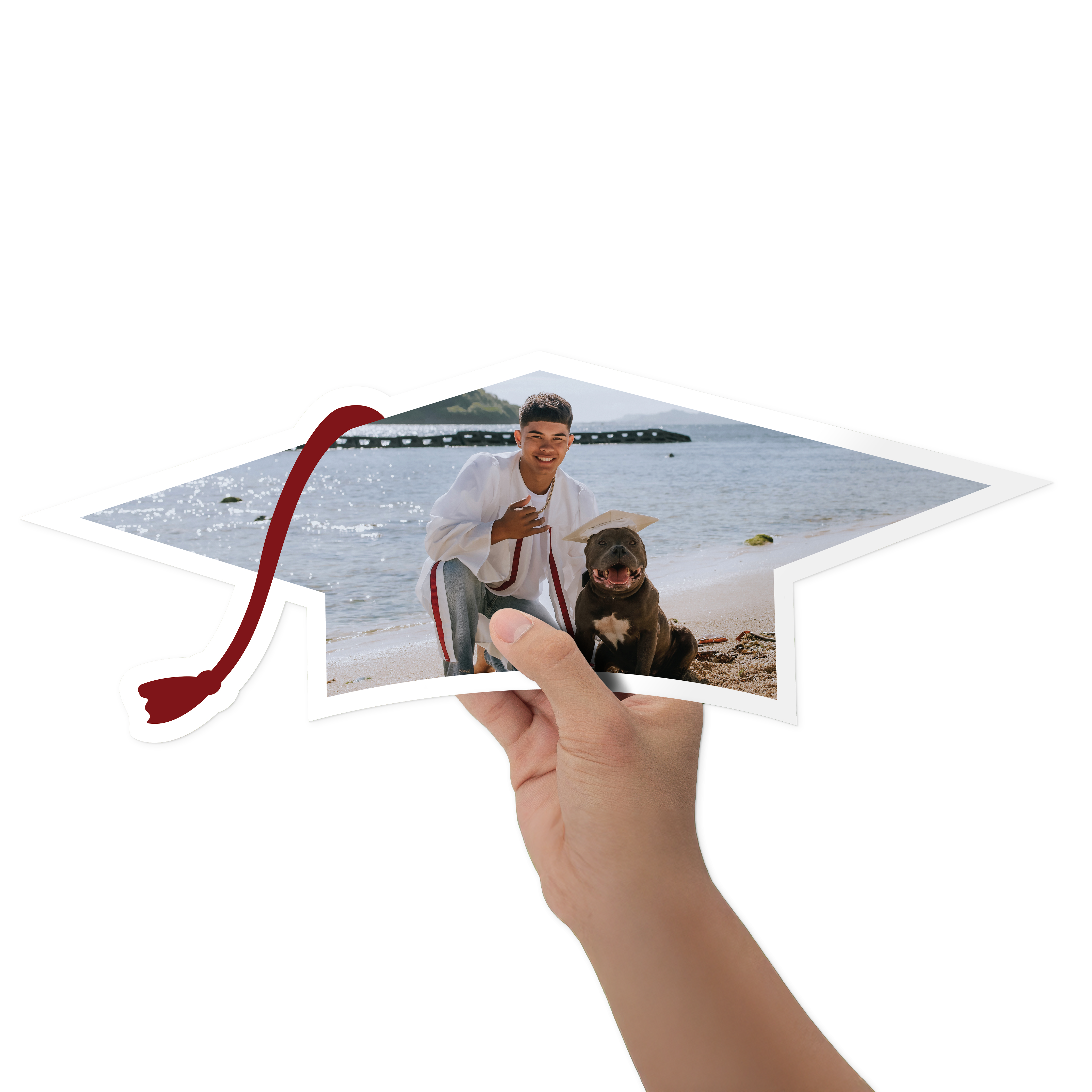 A person holds a cutout graduation cap sign featuring a full photo of grad, with a tassel on the left side.